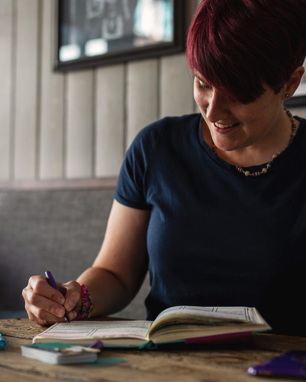Jeni, Founder of The Focused Woman Collective, writing in a notebook